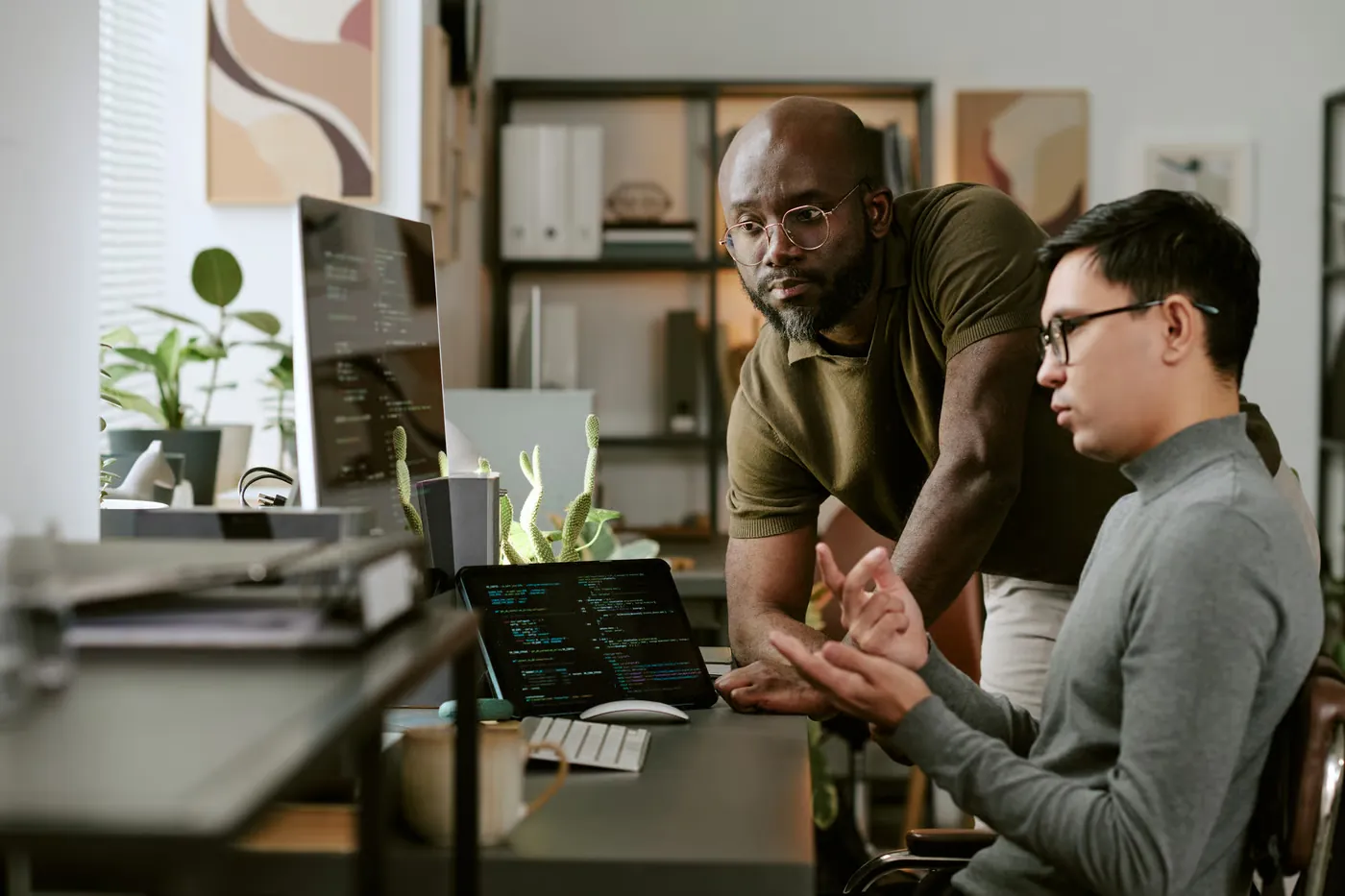 Two engineers reviewing code together at a desk in a studio.